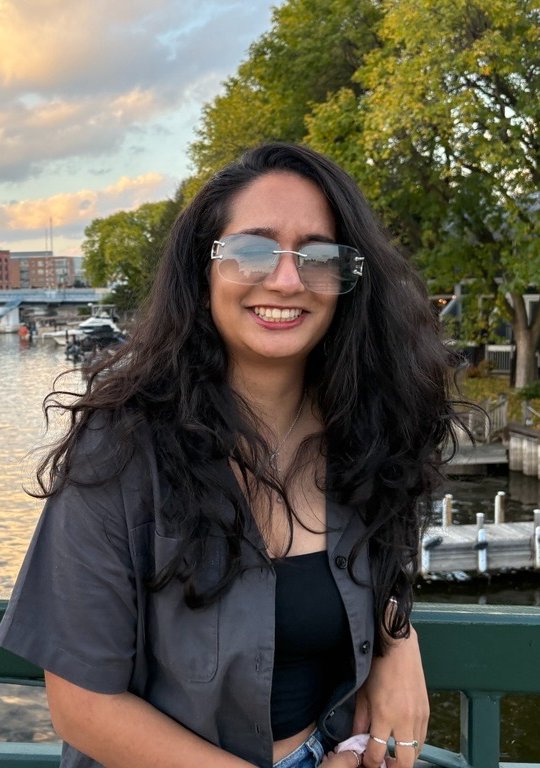 Sana smiling on a bridge over a river at sunset
